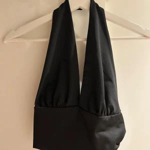 Svart halterneck topp från SHEIN - Säljer en svart halterneck topp från SHEIN i storlek S. Materialet är mjukt och stretchigt med 95% polyester och 5% elastan. Perfekt för dig som gillar en croppad och trendig stil.