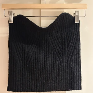 Svart ribbad tubtopp från SHEIN - Svart tubtopp från SHEIN i storlek M. Toppen är ribbad med snygg struktur och har en bandeauformad siluett. Tillverkad i mjuk polyester som sitter skönt mot kroppen. Perfekt för dig som gillar minimalistisk och stilren look.