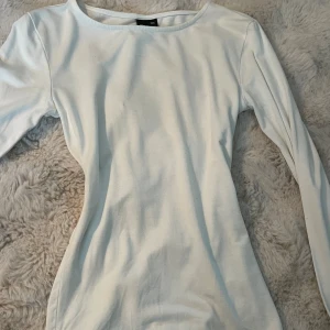 Vit långärmad topp från Gina Tricot - Säljer en stilren vit långärmad topp från Gina Tricot i storlek XXS. Toppen har en rund halsringning och är gjord i mjuk bomull som känns skön mot huden. Perfekt att matcha med jeans eller kjol för en clean look. Armarna har slits.