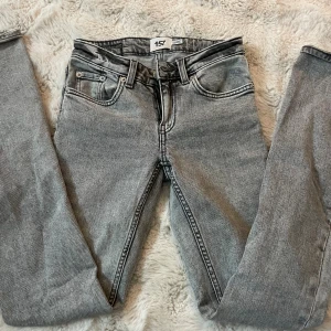 Grå jeans  - Snygga grå jeans från 157 med klassisk femficksdesign och bootcut. Jeansen har en cool tvättad look och svarta detaljer vid midjan. Passar dig som gillar enkel och stilren streetstil. Materialet är slitstarkt denim och midjan är normal. 