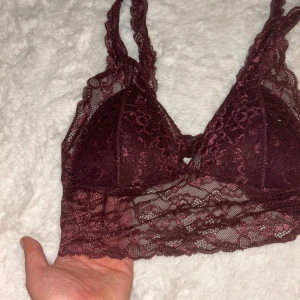 Vinröd spets topp - Superfin vinröd topp/bh med bred spetskant och blommigt mönster i spets. Axelbanden är också i spets och toppen har en v-ringad form. Utsidan är transparent spets, med ilägg vid brösten. Använd någon gång men inte mkt. Ganska stretchig runt om men vid brösten passar den på B kupor.