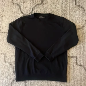 Mörkblå sweatshirt från Dressmann - En stilren mörkblå sweatshirt från Dressmann i storlek L. Tröjan har rund hals, långa ärmar och ribbade muddar vid ärmslut och nederkant. Perfekt för dig som gillar enkel och klassisk look. Materialet känns mjukt och bekvämt mot huden har några små små  solbrända märken som knappt syns, priset är inte spikat så kom med förslag. 