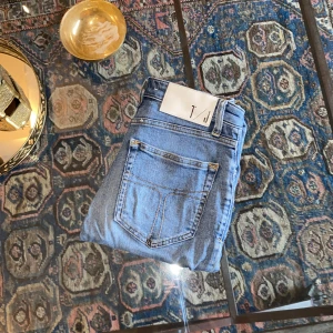 Tiger of Sweden ljusblå jeans - Snygga ljusblå jeans från Tiger of Sweden med klassisk femficksdesign och vit patch med T/J-logga bak. Jeansen är i väldigt bra skick och knappast använda. Storlek är : W27 och L32. Bara o höra av er vid frågor 🤩