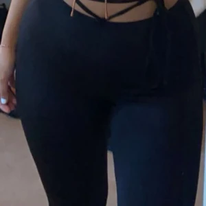 Svarta vida byxor med snörning - Svarta byxor från Divided med vida ben och snygg snörning i midjan. Mjukt material som känns skönt mot huden och ger en avslappnad vibe. Perfekta att styla med crop top eller hoodie för en chill look.