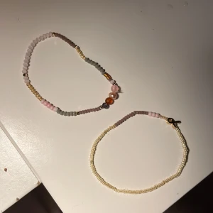 Två pärlarmband i pastellfärger - Säljer två handgjorda armband med små pärlor i pastelliga toner. Det ena armbandet har mix av rosa, grå, guld och orange pärlor, medan det andra är mer diskret med ljusgula och rosa pärlor. Perfekta accessoarer för en söt och personlig stil.