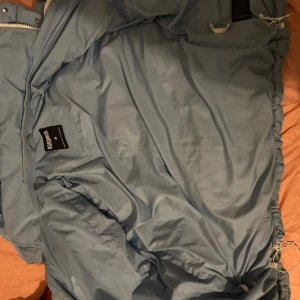 Ljusblå pufferjacka från Hoodrich - , Säljer min Hoodrich puffer jacket i färgen Sky Blue. Jackan är helt ny och aldrig använd ute, men den har lite smuts och en liten svart fläck (går säkert bort i tvätt). Ingen hål, inga skador. Riktigt snygg och varm jacka med premium känsla