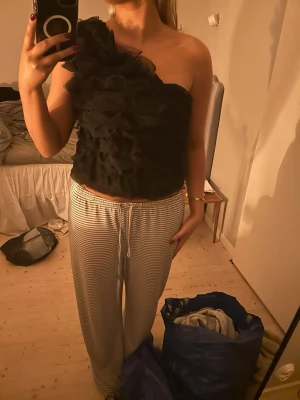 Svart oneshoulder volangtop - Säljer en svart oneshoulder topp med volangdetaljer. 