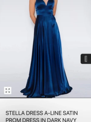 Mörkblå balklänning i satin - Elegant mörkblå långklänning i glansig satin med v-ringad urringning. Klänningen har en klassisk A-linjeformad siluett som faller snyggt och ger en lyxig känsla. Perfekt för bal eller festliga tillfällen.🩵🩵💖
