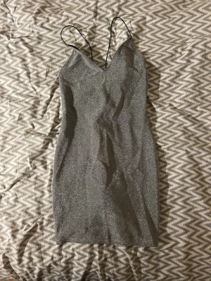 Glittrig silver klänning från Divided - Säljer en glittrig silverfärgad kort klänning från Divided i strlk S. Klänningen har tunna axelband och en smickrande v-ringning samt öppen rygg. Skriv vid frågor!🥰
