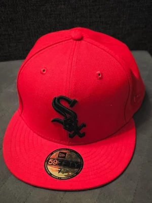 Röd New Era White Sox keps - Snygg röd keps från New Era med Chicago White Sox-logga i svart framtill och broderad 2003 All-Star Game patch på sidan. Klassisk 59FIFTY-modell med platt skärm och strukturerad passform. Perfekt för dig som gillar sportig streetstyle och vill sticka ut. Priset är ej hugget i sten. Den är använd 1 gång. Hör av er vid frågor! 
