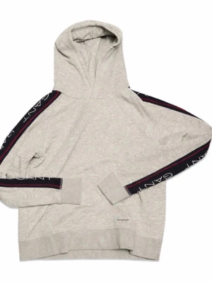 Grå hoodie från Gant med logga - Snygg grå hoodie från Gant med huva och svarta loggband längs ärmarna där det står 'GANT' i vitt. Hoodien har en klassisk passform, ribbade muddar och är tillverkad i mjukt bomullsmaterial. Perfekt för en avslappnad och trendig look.