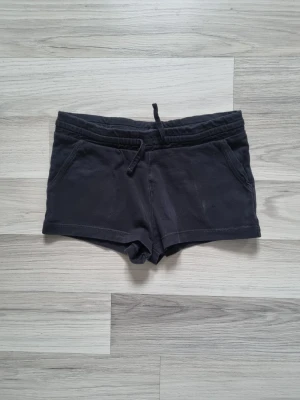 Svarta shorts med snörning - Säljer ett par svarta shorts i mjuk bomull med snörning i midjan och två fickor fram. Perfekta för chill dagar eller träning. Klassisk och enkel design som är lätt att matcha.