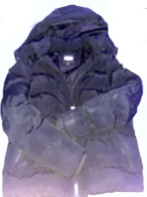 Svart pufferjacka från Kappa - Säljer en svart pufferjacka från Kappa med huva och dragkedja framtill. Jackan har en quiltad design och är tillverkad i syntetmaterial, perfekt för kalla dagar. Klassisk passform och enkel stil som funkar till det mesta.