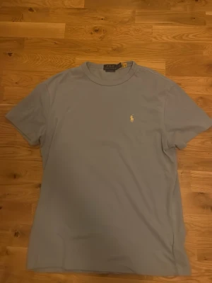 Ljusblå t-shirt från Polo Ralph Lauren - Snygg ljusblå t-shirt från Polo Ralph Lauren med vit logga. Säljer då den är för stor. Helt ny, endast använd 1 gång