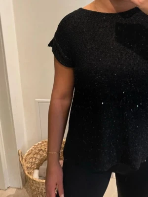 Svart stickad topp med öppen rygg - Oanvänd festlig tröja med små paljetter. Öppning på ryggen. Köpt i Zara. Storlek S.