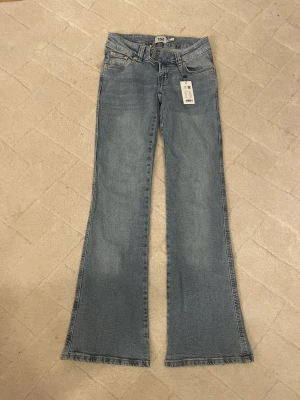 Blå bootcut jeans  - Snygga ljusblå bootcut jeans med klassisk fram ficksdesign och broderade detaljer på bakfickorna. Jeansen har normal passform och är tillverkade i mjukt denimtyg som ger en avslappnad look.