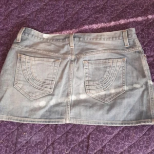 Ljusblå jeanskjol med fickor - Snygg ljusblå jeanskjol med klassiska fickor både fram och bak samt bälteshällor. Kjolen har en rak passform och stängs med knapp och dragkedja framtill. Perfekt för dig som gillar en enkel men trendig stil. Älskar den men säljer den då den tyvärr ej passar mig. 