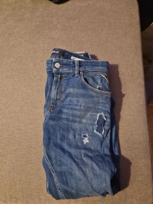 Blå Replay Marty jeans slim fit - Säljer ett par blå Replay Marty jeans i slim fit med slitna detaljer och klassisk femficksmodell. Jeansen har normal midja och är tillverkade i mjukt denimtyg som ger en skön passform. Perfekta för dig som gillar en avslappnad men snygg stil.  På jeansen står det 26 och jag antar att det ska vara storleken. Jag är själv 182 lång och dom passar perfekt för ca 175-180cm långa 