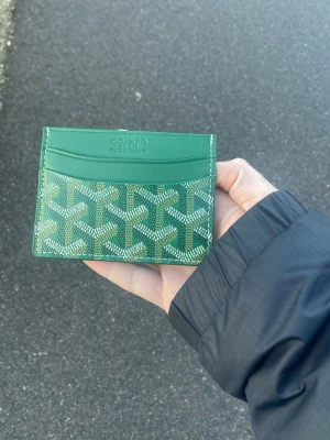 Grön plånbok med mönster - Snygg matt grön plånbok  med ikoniskt grafiskt mönster i vitt och grönt. Plånboken har flera kortfack och är tillverkad i skinn med en lyxig känsla. Perfekt för dig som vill ha något både stilrent och unikt i fickan.