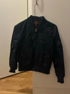 Svart Alphajacka - Svart Alpha Industries-jacka i unisexmodell – en tidlös klassiker med attityd. Jackan har en stilren design som funkar lika bra till vardags som till streetwear-look. Slitstarkt material, genomtänkta detaljer och bekväm passform gör den till ett pålitligt val säsong efter säsong.