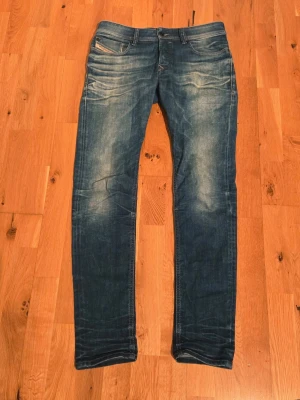 Blå diesel jeans med slitningar - Snygga blå dieseljeans med slitningar och tvättade detaljer. Jeansen har klassisk femficksdesign och smal passform hela vägen ner. Perfekta för en trendig och avslappnad look. Materialet är jeans i bomull med lite stretch för extra komfort.
