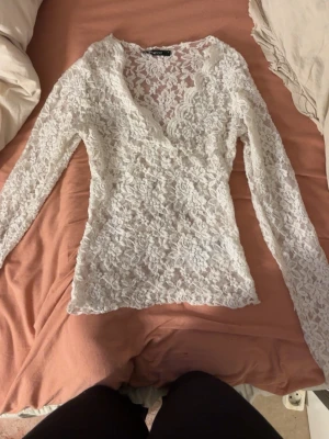 Vit spetsblus med v-ringning - Superfin vit spetsblus från gina tricot med omlott och v-ringning. Långärmad modell i genombruten spets.