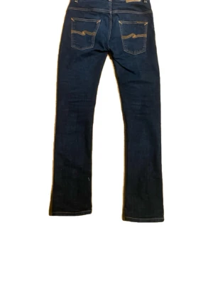Mörkblå skinny jeans med slitningar - Mörkblå skinny jeans med slitna detaljer framtill och klassiska bakfickor med broderad söm. Jeansen har en smal passform och är tillverkade i stretchig denim för extra komfort. Perfekta för en trendig och avslappnad look.