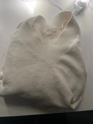 Vit stickad tröja från Gina Tricot - Större i stolek skulen säga runt 146/152 Säljer en krämvit stickad tröja från Gina Tricot med bred ribbad V-ringning. Tröjan har en mjuk och mysig känsla, perfekt för kyliga dagar. Enkel och stilren design som passar till det mesta.