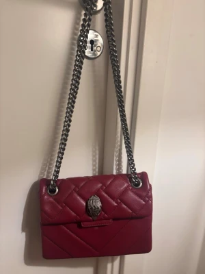 Vinröd väska❤️‍🔥 - Snygg vinröd väska liknade  Kurt Geiger skinn med silverfärgad kedjerem och ikoniskt örnhuvud som spänne. Perfekt accessoar för att lyfta din outfit!❣️❣️❣️❣️❣️