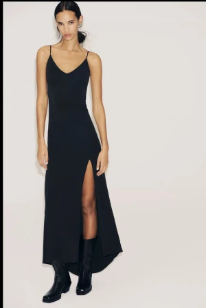 Svart långklänning med slits - Snygg svart långklänning med smala axelband och öppen rygg. Klänningen har en hög slits framtill. Så otroligt snygg och elegant! Perfekt för tillställningar, fester och middagar. Endast använd vid 1 tillfälle, så helt i nyskick. Klänningen är helt slutsåld, så går inte att få tag i. Köpt för 400 kr! Skriv för fler bilder❣️