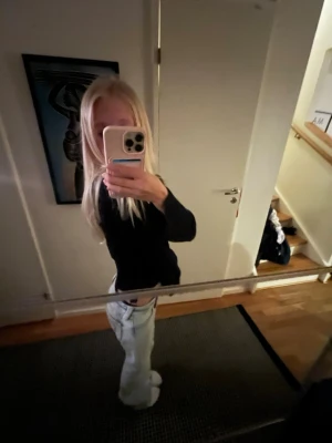 Svart omlott kofta med knyt - Säljer en svart omlott kofta med knyt i sidan. Koftan har v-ringning och är långärmad, perfekt att slänga på över en t-shirt eller linne. Den är stickad och har en lite croppad passform som ger en snygg siluett.