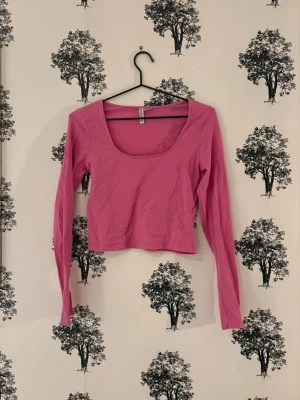 Rosa långärmad topp från H&M - En enkel och snygg rosa långärmad topp från H&M Basic. Modellen är croppad med en bred, rundad urringning och har en tight passform. Perfekt att styla med höga jeans eller kjol för en clean look.