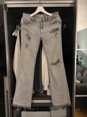 Grå bootcut jeans med slitningar - Det Snygga grå jeans från ONLY med trendiga slitningar framtill. Storlek 40 men passar även mig med storlek 38 