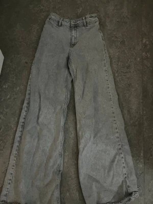 Grå wide jeans från MNG Denim - Säljer ett par gråa jeans från MNG Denim i storlek 32. Jeansen har en loose och wide passform med hög midja och raka, vida ben. Materialet är klassisk denim i bomull och byxorna har råa, fransiga benslut för en avslappnad vibe.