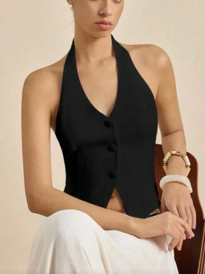 Svart korsettopp med knytning - Säljer en svart korsettopp med halterneck och djup v-ringning. Toppen har knappar framtill och knytning i ryggen för en snygg passform. Perfekt att styla med både kjol och jeans för en trendig look.