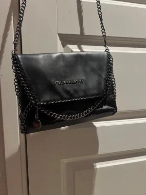 Stella McCartney  - Säljer min Stella McCartney Falabella crossbody i svart. Klassisk modell med de ikoniska kedjedetaljerna. Väskan är använd men i gott skick. Viss mjukhet/veck i materialet förekommer, vilket är normalt för Falabella-modellen och påverkar inte användningen.  Nypris: 7 960 kr Material: Veganskt läder (eco leather)  Perfekt som vardagsväska eller till kväll/finare tillfällen. Förvarad i rökfritt hem.  Pris kan diskuteras vid snabb affär. 