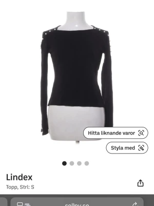 Svart långärmad topp från Lindex - Säljer en svart långärmad topp från Lindex med dekorativa knappar på axlarna och ärmarna. Toppen har en rak, något tight passform och är tillverkad i ett mjukt material som känns skönt mot huden. Perfekt att matcha med jeans eller kjol.