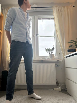 Ljusblå bomullsskjorta med knappar - Säljer en stilren ljusblå skjorta i bomull med klassisk krage och knäppning framtill. Skjortan har lång ärm och en bröstficka, perfekt att bära öppen över en t-shirt för en avslappnad look.