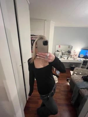 Svart långärmad topp med fyrkantig ringning - Säljer en svart långärmad topp med snygg fyrkantig ringning. Modellen är tight och enkel, perfekt att styla med jeans eller kjol. Tidlös och stilren design som funkar till många olika looks.