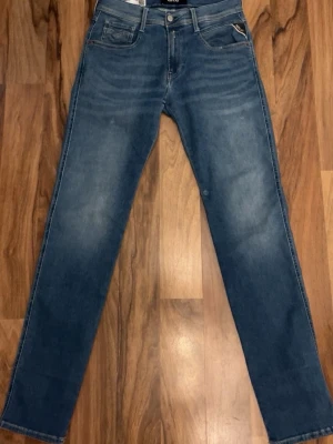 Reaplay jeans  - Säljer ett par blå Replay Hyperflex jeans med klassisk femficksdesign och raka ben. Jeansen har en snygg tvätt med lätt slitningar och är tillverkade i stretchigt jeansmaterial för extra komfort. Passar perfekt till en avslappnad stil. STORLEK 29/32