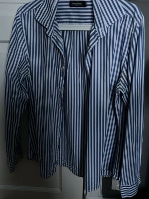 Blåvit randig skjorta Dressmann - Säljer en blåvit randig skjorta från Dressmann i slim fit-modell. Skjortan har klassisk krage, långa ärmar och knäppning framtill. Tillverkad i bomull för en skön känsla och stilren look.