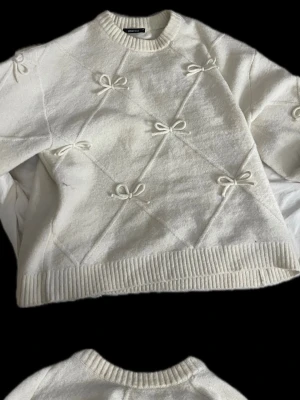 Stickad tröja - Tjock Vit stickad tröja med rosetter, mycket bra skick aldrig använd. Storlek M