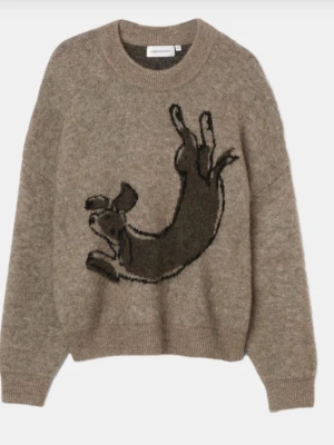 Carin Wester stickad tröja - Säljer en beige stickad tröja från Carin Wester med en stor, lekfull hundillustration framtill. Tröjan har rund halsringning, ribbade muddar och lång ärm. Perfekt för dig som vill ha något mysigt och unikt i garderoben.