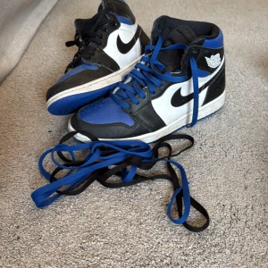 Nike Air Jordans i blått, svart och vitt - Säljer ett par Nike Air Jordans high-top sneakers i blått, svart och vitt. Skorna har både blå och svarta skosnören, vit sula, crease protecters och klassisk Nike-logga på sidan. Perfekta för dig som gillar streetwear och vill sticka ut med färg. (Låda ingår inte tyvärr) köptes för 4000kr på hypestein