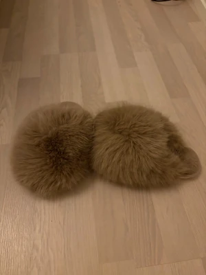 Bruna fluffiga slippers med päls - Supermysiga slippers i brun färg med tjockt, fluffigt pälsmaterial över hela ovandelen. Sulan är vit och har ett diskret mönster undertill. Perfekta att glida runt i hemma för en cozy vibe. Oanvända! Strl 36-37