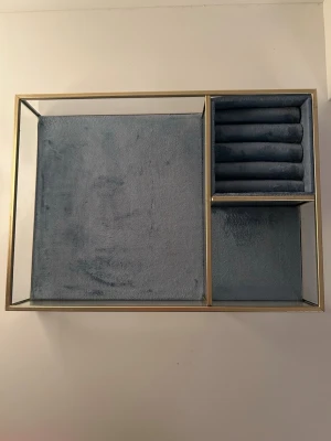 Blå smyckesbricka i sammet från Flying Tiger - Blå smyckesbricka i sammet med guldfärgade kanter från Flying Tiger. Se bilderna och zooma in för att se ytterst små ”defekter” i form av att guldkanterna har skrapats lite. Detta förekommer även på dess baksida, se bilderna och zooma in på kanterna. I övrigt är det är inget som påverkar dess funktion och brickan är i mycket bra skick. 