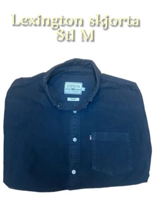 Mörkblå skjorta från Lexington M - Klassisk mörkblå skjorta från Lexington i storlek M. Skjortan har lång ärm, bröstficka och knappar framtill. Tillverkad i mjuk bomull och passar perfekt till en avslappnad men ändå stilren look. Hör gärna av dig vid frågor🙂skjortan är urtvättat