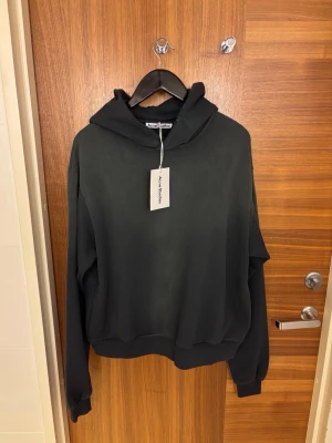  Acne studios hoodie - Säljer en svart hoodie från Acne Studios med tryck på ryggen: Acne Studios Stockholm 1996. Hoodien har en avslappnad, oversize passform och är tillverkad i en mjuk, ekologiskt odlad bomullsblandning med återvunnen polyester. Ett stilrent och bekvämt plagg som funkar lika bra året runt. Hoodien har en lite sliten/ urtvättad touch som är en del av designen. 