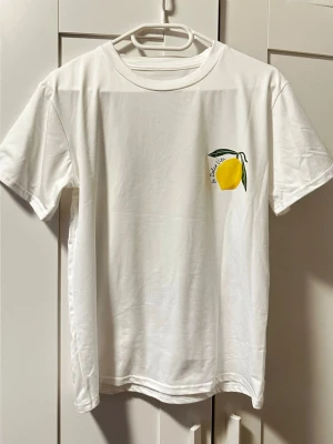 Vit t-shirt med citrontryck - Säljer en vit t-shirt i bomull med stort citrontryck. Nyskick, standard storlek (S/M) 