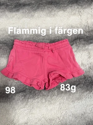 Rosa shorts med volangkant och snörning - Söta rosa shorts med volang soppar och snörning i midjan. De har en elastisk midja för extra komfort och är perfekta för varma dagar. 🌸Flammig i färgen. Storlek 98 